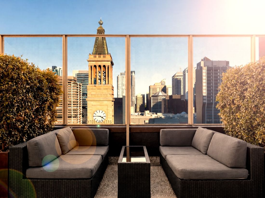 Couches and cityscape view through large windows at SIXTEEN ANTLERS ROOFTOP BAR, Pullman Brisbane King George Square.