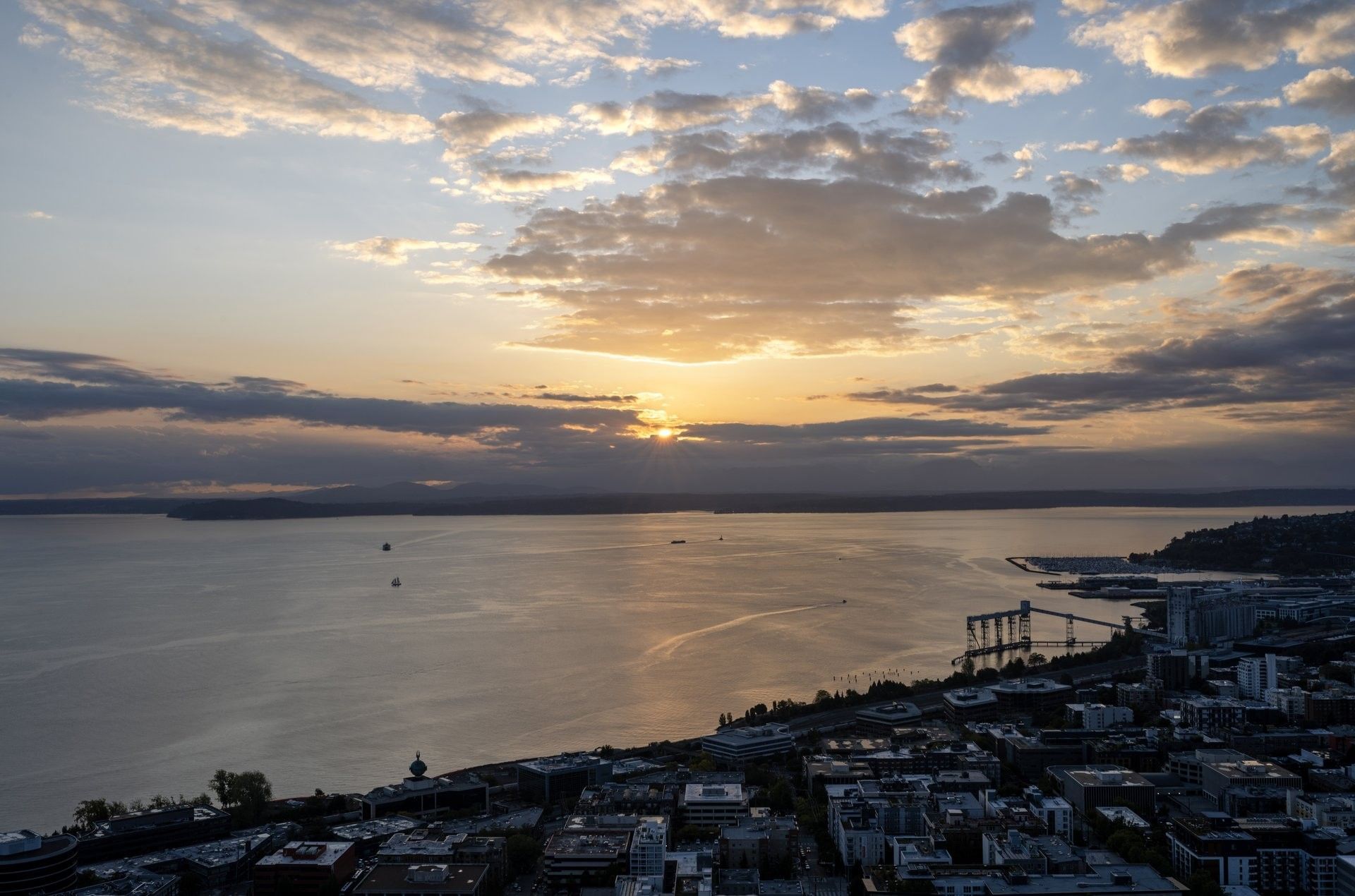 Elevated view of a bay with boats and city lights at sunset under clouds near Warwick Seattle