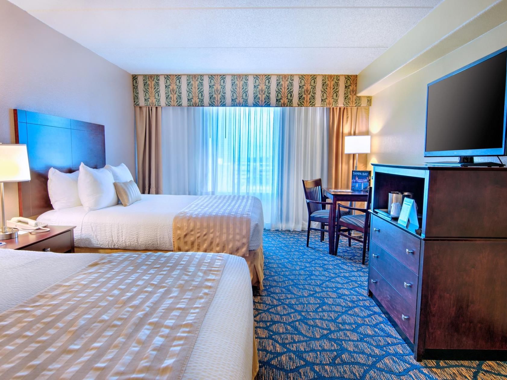 TV & work desk facing Two Queen Beds in a room at The Barrymore Hotel