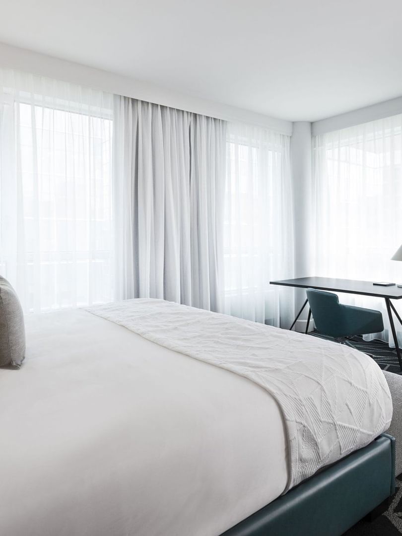 Warwick Premier Suite with a bed and workspace near the window at Warwick Le Crystal Montreal