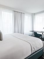 Warwick Premier Suite with a bed and workspace near the window at Warwick Le Crystal Montreal