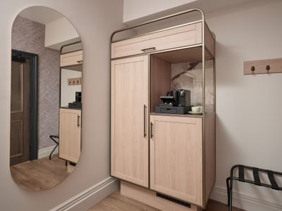 Stylish coffee station and wardrobe with a large oval mirror in a suite at The Met Hotel Leeds, England