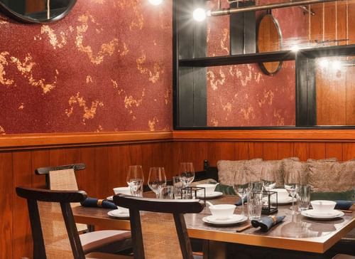 White Lotus restaurant table set with plates, glasses, and utensils in a warmly lit, industrial-style restaurant.