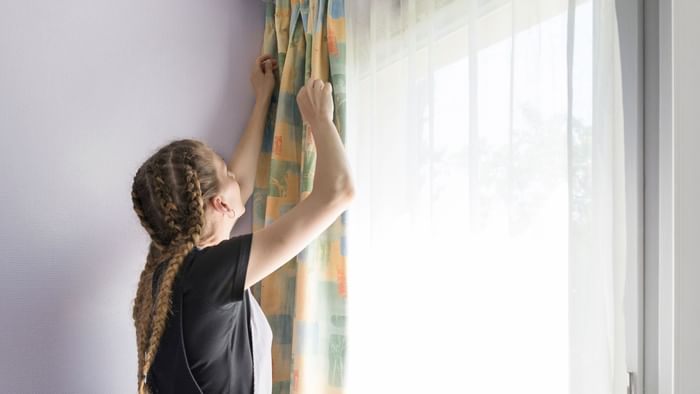 A maid preparing curtains in a room at Hotel Valence East