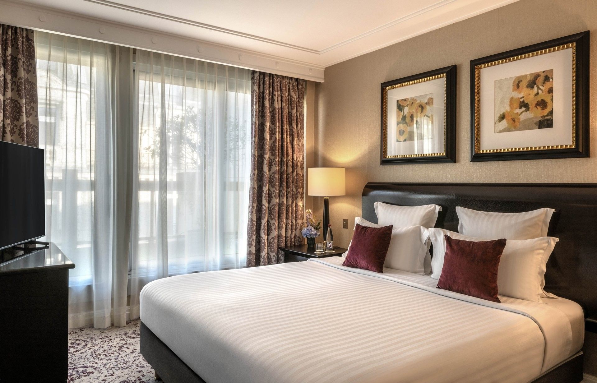 White bed with burgundy pillows by a side table in Elegant Executive Suite with Terrace at Warwick Paris Champs Elysées
