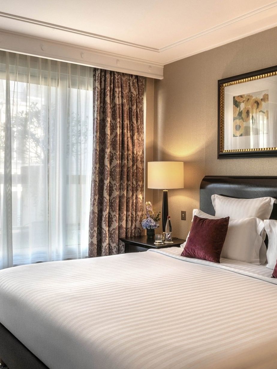 Élégante suite exécutive avec terrasse, dotée d'un lit king size, d'oreillers moelleux et d'une vue imprenable depuis la fenêtre, au Warwick Champs-Élysées Paris.
