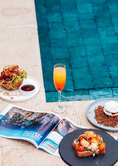 Open a magazine near a cocktail and food by the pool, among
best resort in Roatan, Honduras, Barefoot Cay Resort & Marina