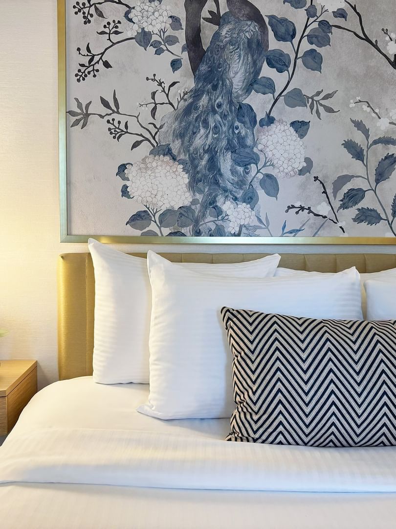 Bed with pillows under a large peacock wall art in Standard Room at Warwick Allerton Chicago