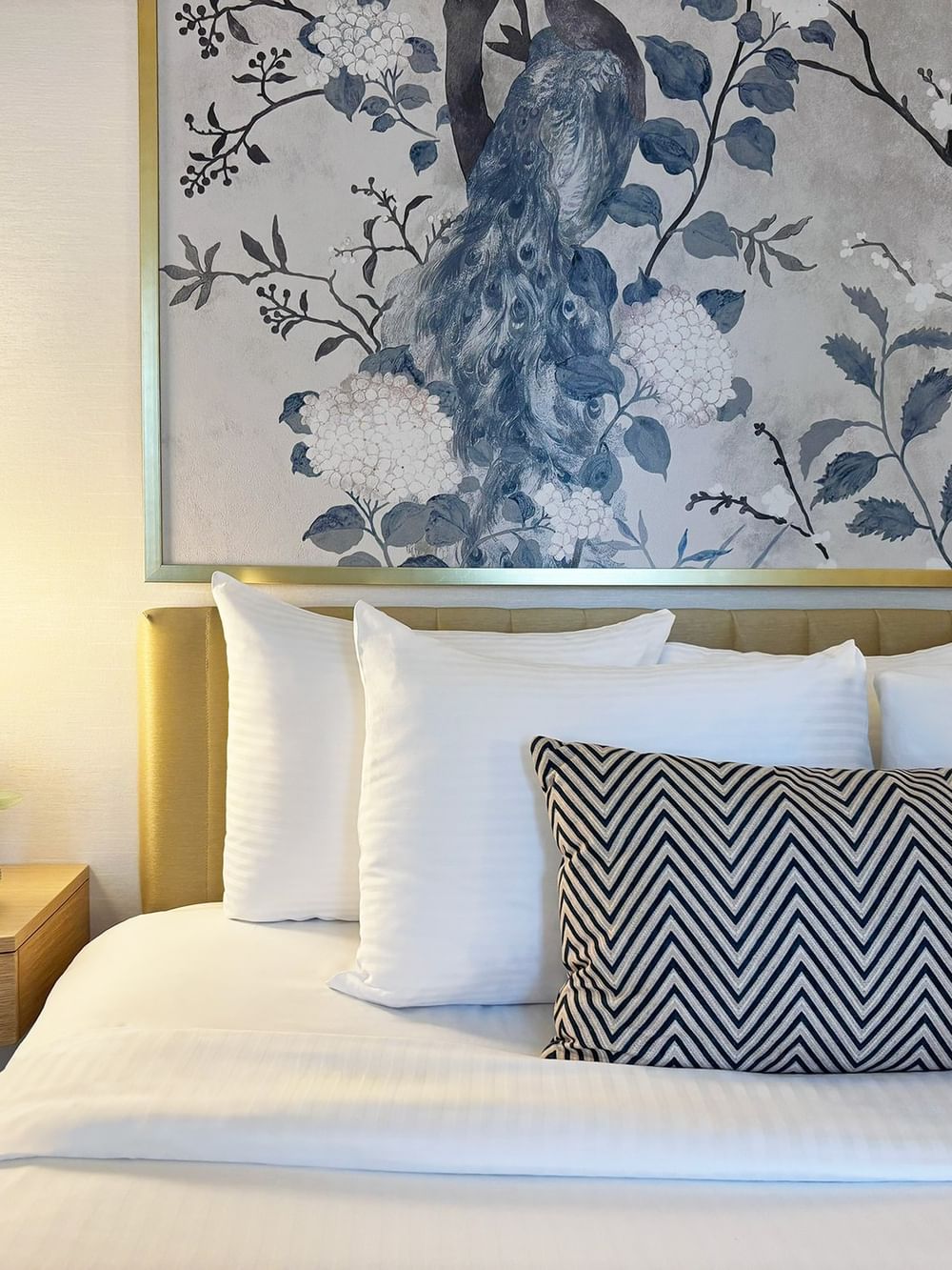 Bed with pillows under a large peacock wall art in Standard Room at Warwick Allerton Chicago