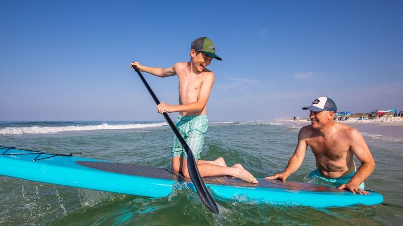 Man teaching a boy surfing at the beach near WaterColor Inn