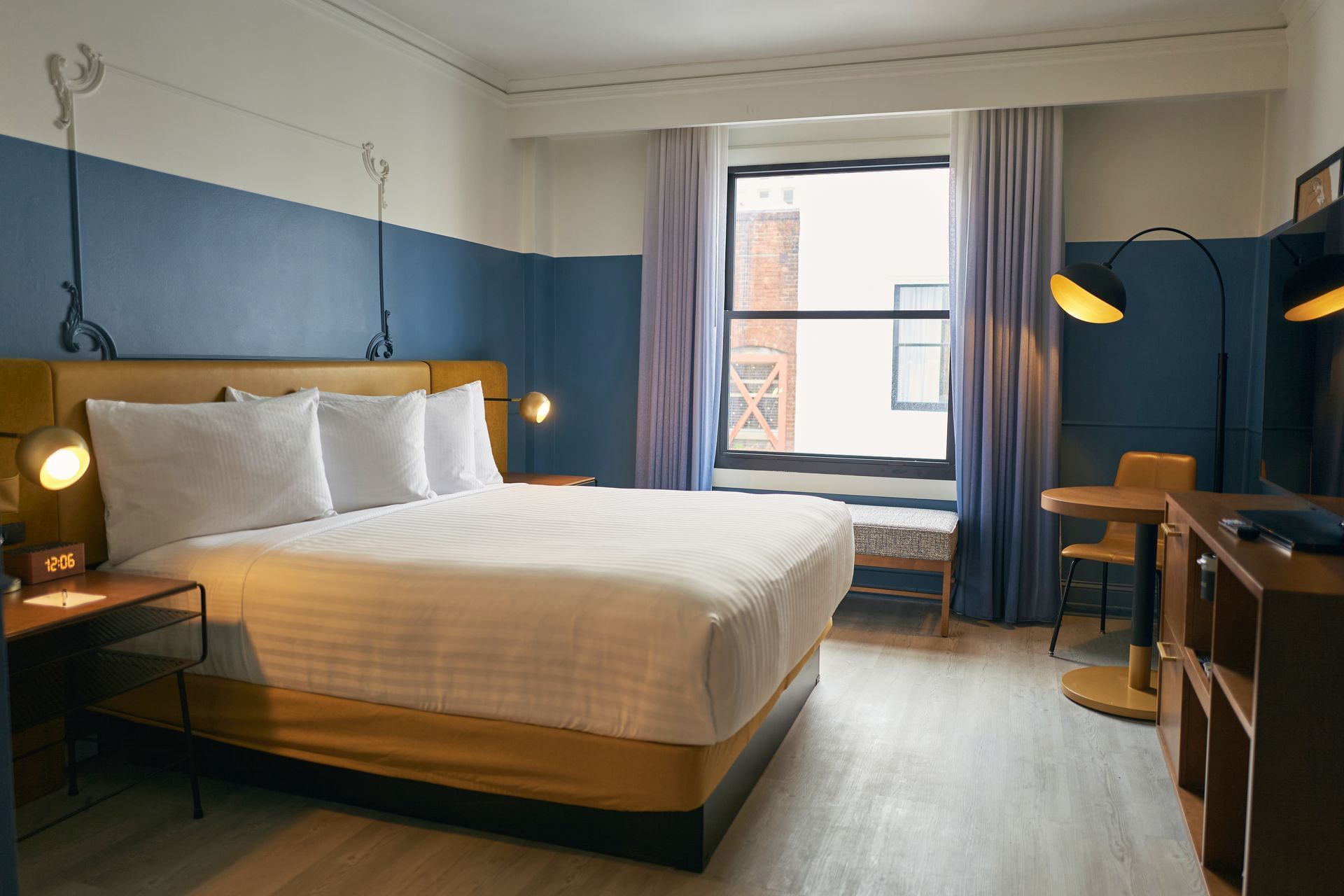 A hotel room with a large bed, window, desk, and TV