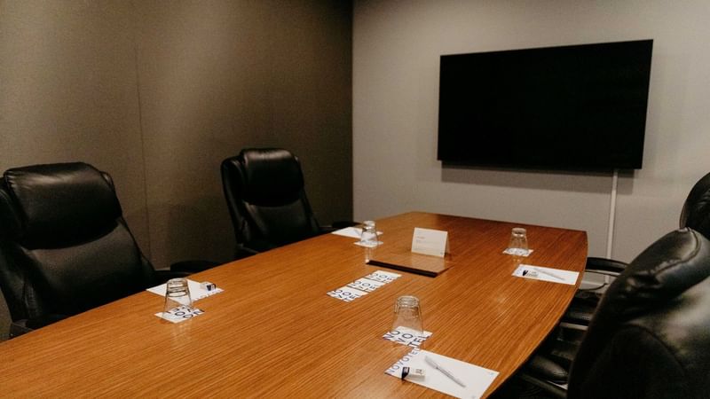 Small boardroom with table, chairs, and a TV at Novotel Sydney Parramatta in Parramatta.