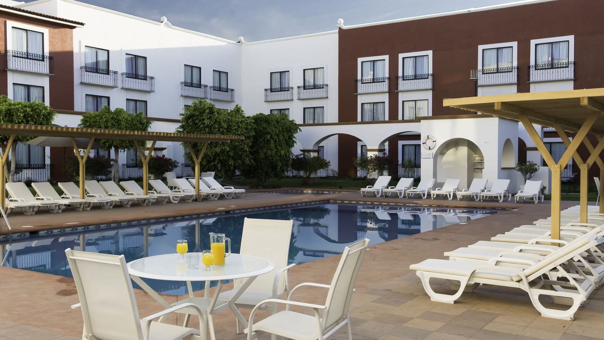 An outdoor dining area by the pool at Fiesta Inn Querétaro