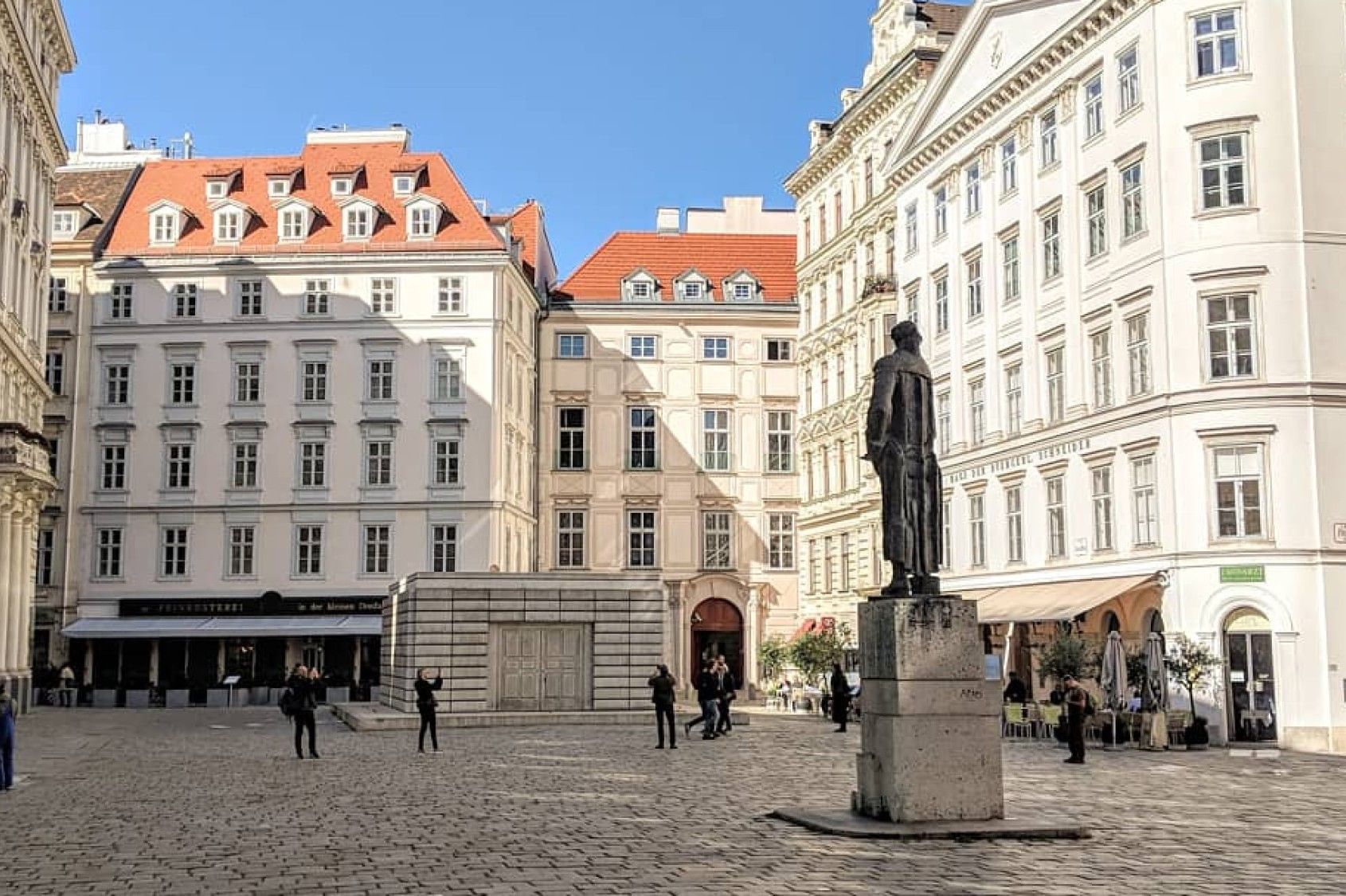 Historic square in Vienna with statue in front of the buildings of the Jewish Museum Vienna and traditional old town architecture