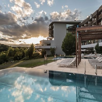 Exterior view of Falkensteiner Balance Resort Stegersbach with outdoor pool & sun loungers