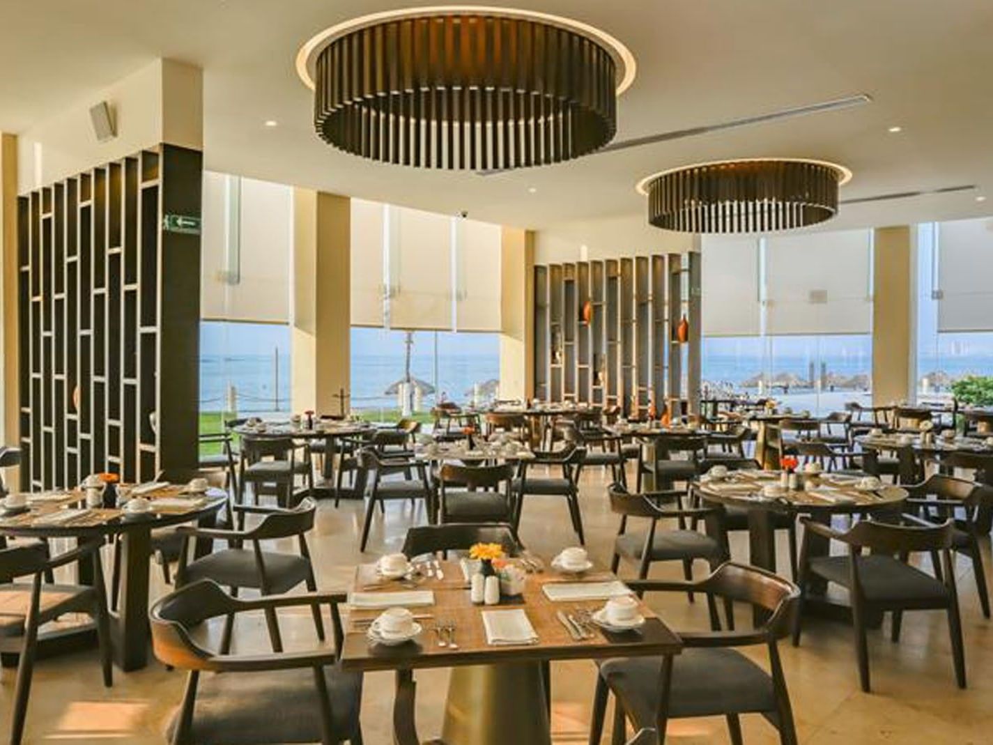 La Huerta restaurant featuring elegant wooden tables and floor-to-ceiling sea views at Camino Real Veracruz