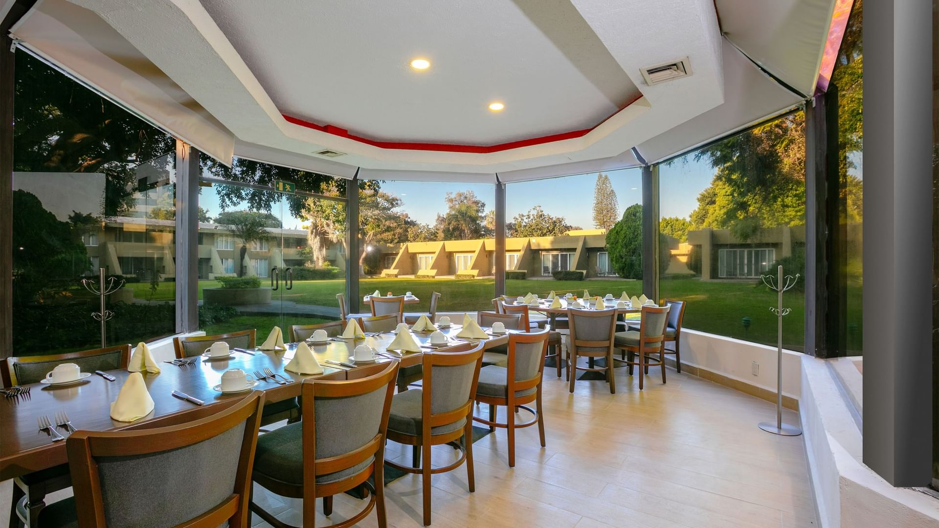 A dining area with large windows overlooking a lush garden at Camino Real Guadalajara in Zapopan