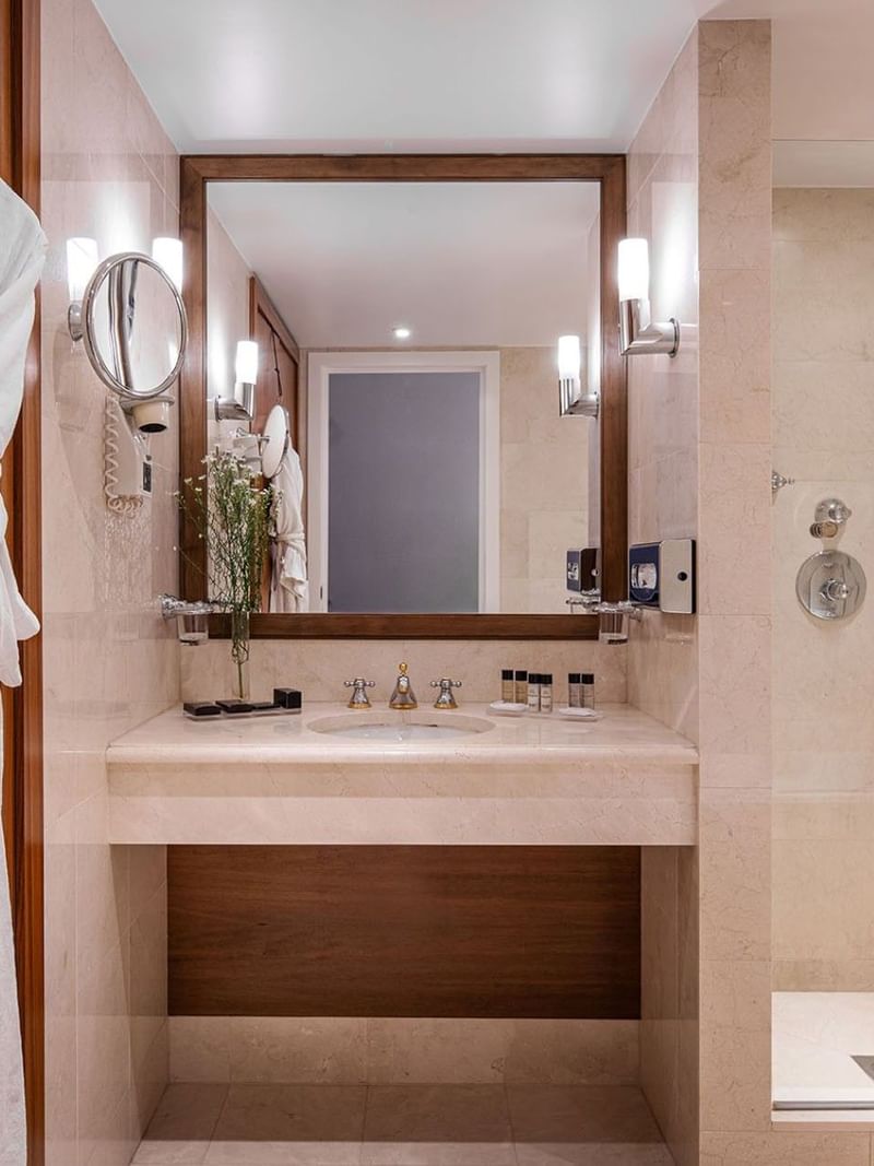 Junior Suite bathroom featuring a marble vanity with a mirror by the glass shower at Warwick Grand Place Brussels