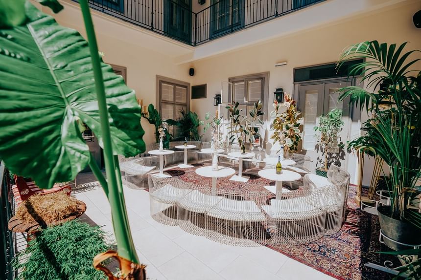 The inner courtyard of the hotel equipped with white seating at white tables surrounded by plants