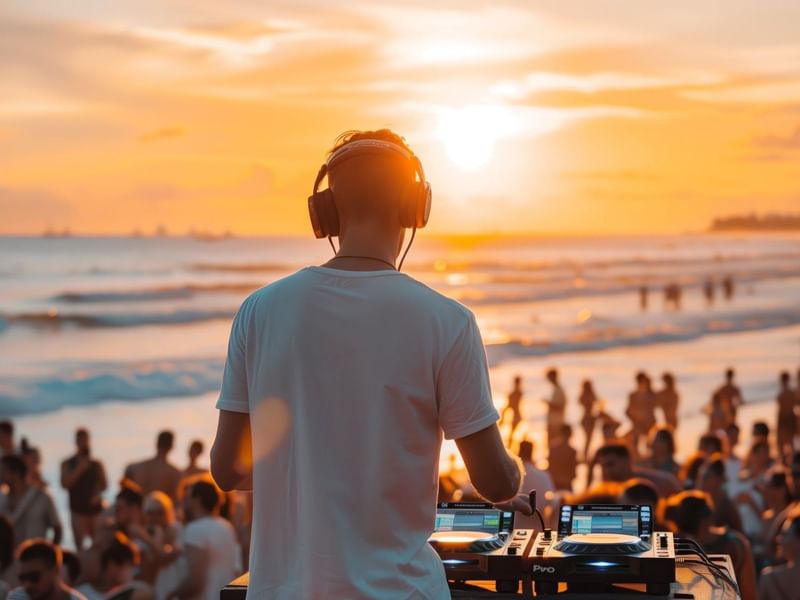 DJ profesional animando a gran multitud en fiesta de playa al atardecer cerca del vibrante Fiesta Americana Funeeq