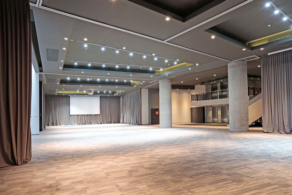 Grande salão vazio com iluminação suave e tela de projeção no fundo no Cumbres Lastarria