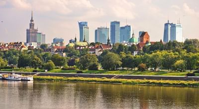 Skyline with a mix of modern high-rises and historic buildings by a river near Polonia Palace Hotel