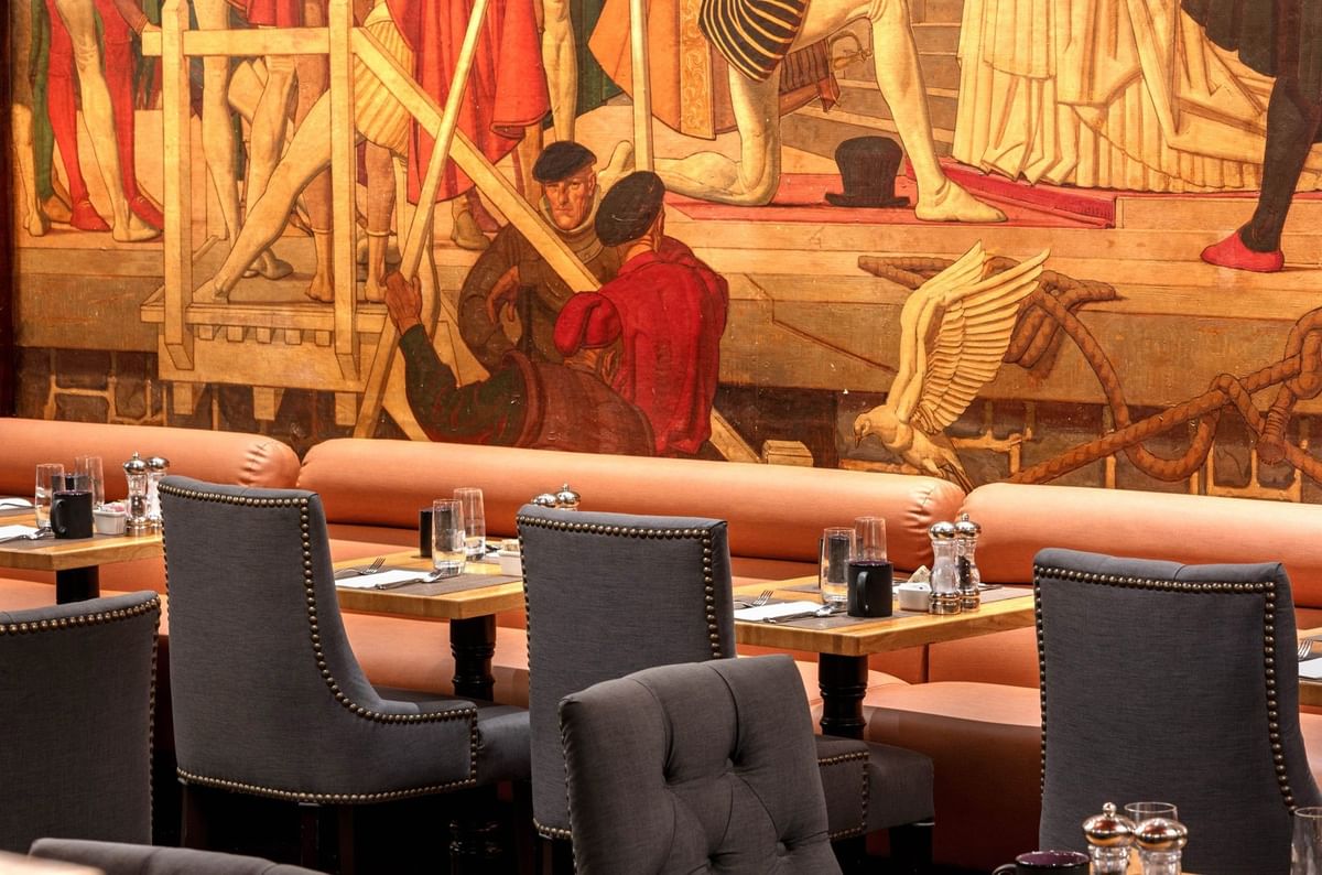 Upscale dining area with gray studded chairs and vibrant wall illustrations in Murals on 54 at Warwick New York