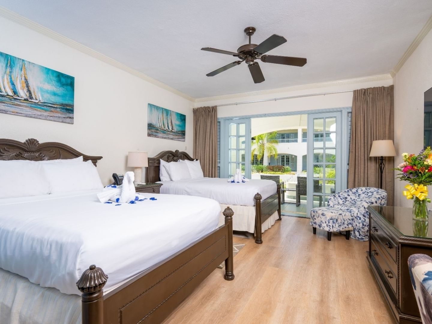 Two twin beds, ceiling fan, and balcony in a room at Savannah Beach Hotel.