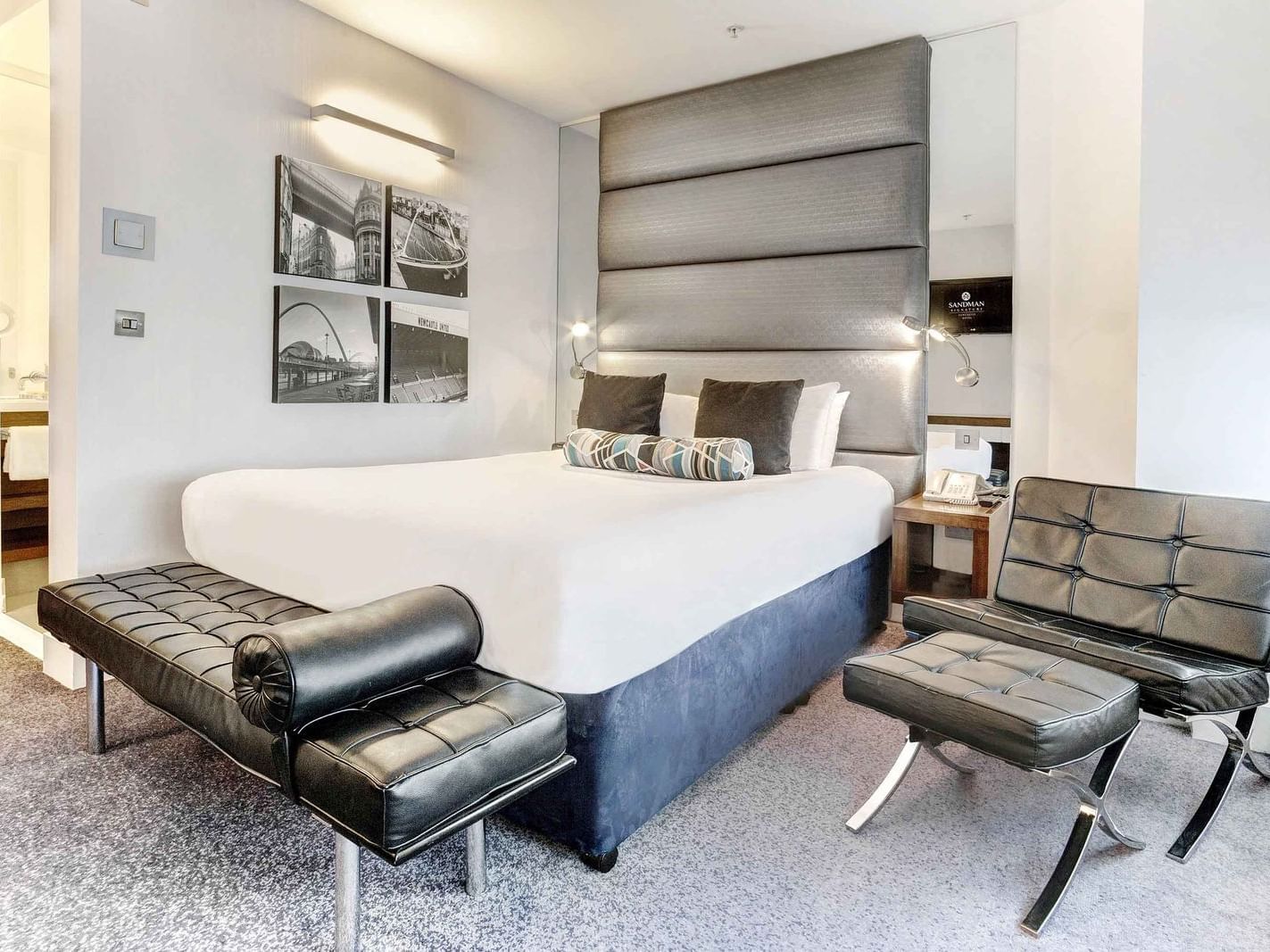 The King Room at Sandman Signature Newcastle Hotel with one king bed (with premium pillow-top) with a two seater black leather chair on the side of the bed with a foot rest