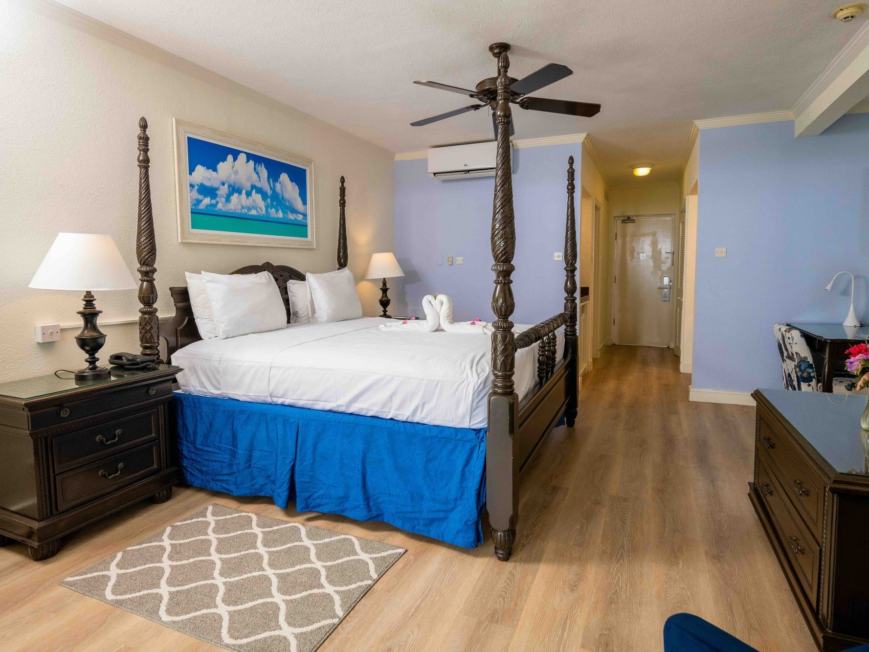Deluxe Beachfront King room with four-poster bed, ceiling fan, and wood floors at Savannah Beach Hotel in Bridgetown