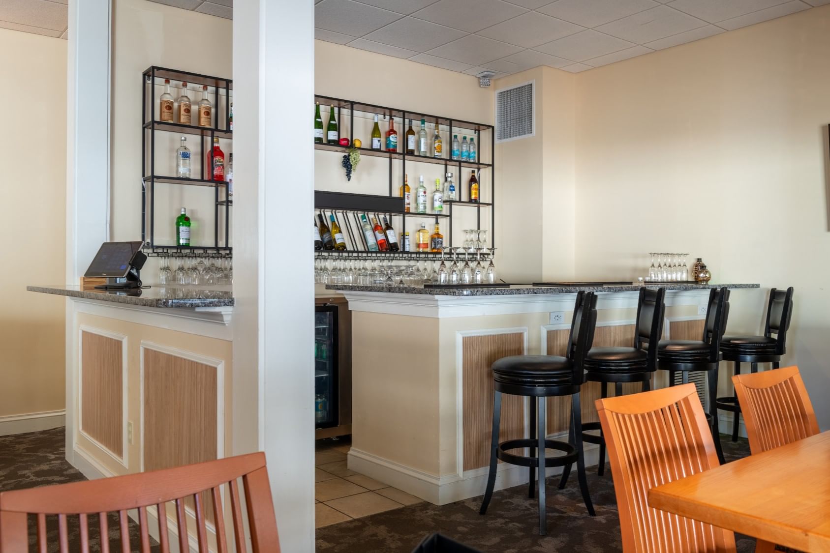 A bar with stools and shelves of liquor