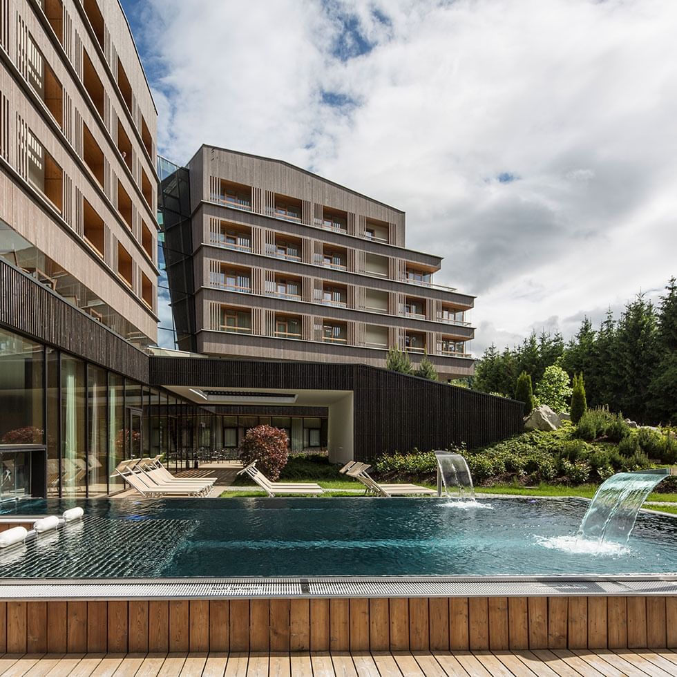 An outdoor pool & sunbeds at Falkensteiner Hotel Schladming