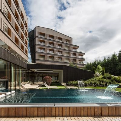 An outdoor pool & sunbeds at Falkensteiner Hotel Schladming