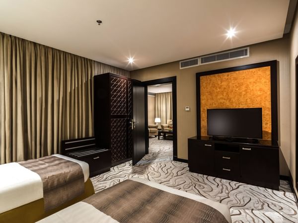Two beds with open doors leading to the living area in Family suite at Warwick Al Khobar