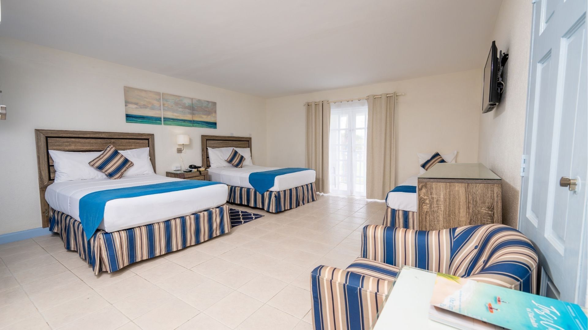 Deluxe Room King features beds with blue striped skirts by an armchair under a flat screen TV at Time Out Hotel