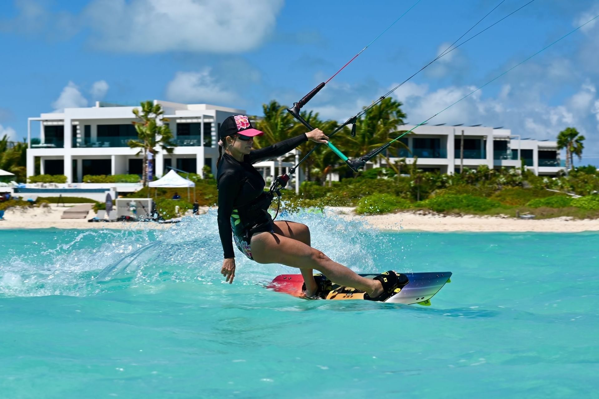 A kiteboarder riding the shallow turquoise water directly in front of H2O life.style.resort on Long Bay Beach, Providenciales
