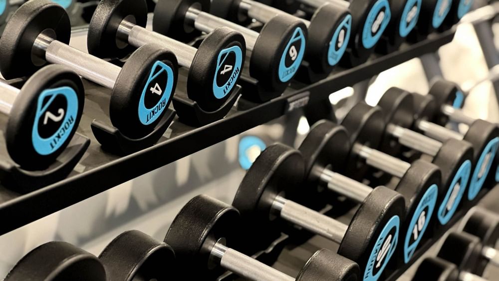 Multiple black dumbbells with blue logos lined up on racks at The Naviti Resort in Korolevu.