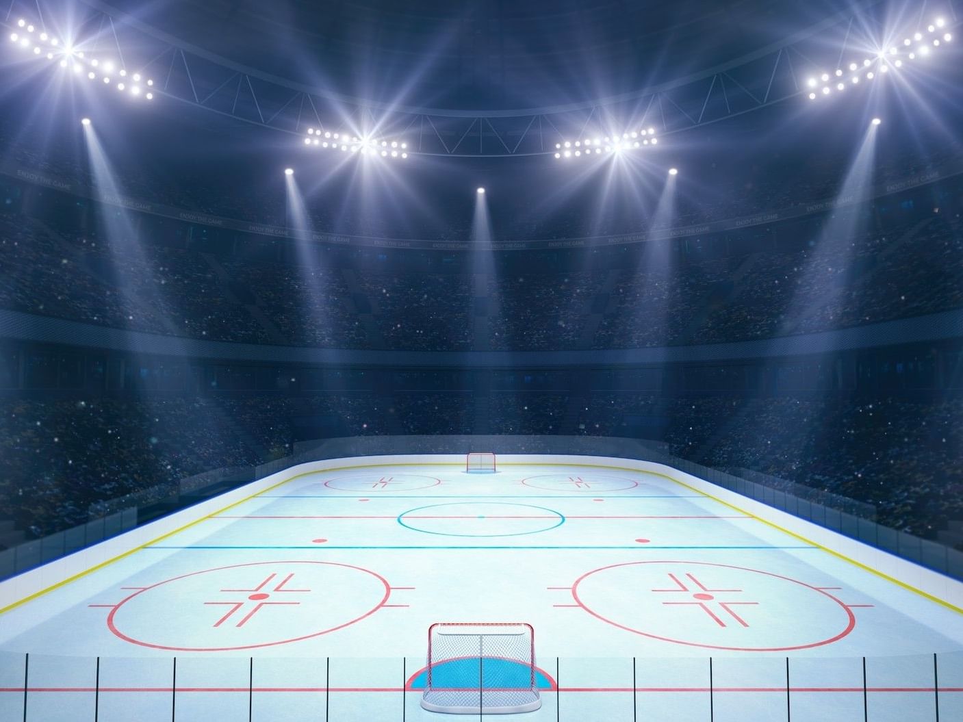 An illuminated hockey rink with a crowd and bright overhead spotlights.