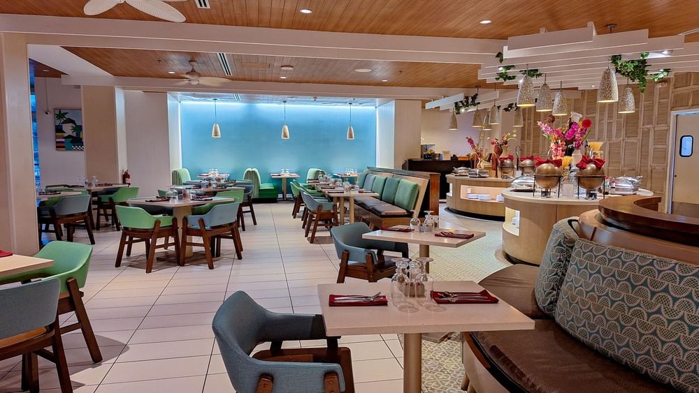 Verandah restaurant interior with  Dining tables by a buffet under stone pendants at Warwick Paradise Island Bahamas
