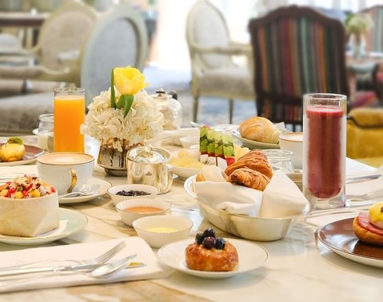 Elegant table set with fruits, pastries, smoothies, and a floral centerpiece at Park Hyatt Saigon