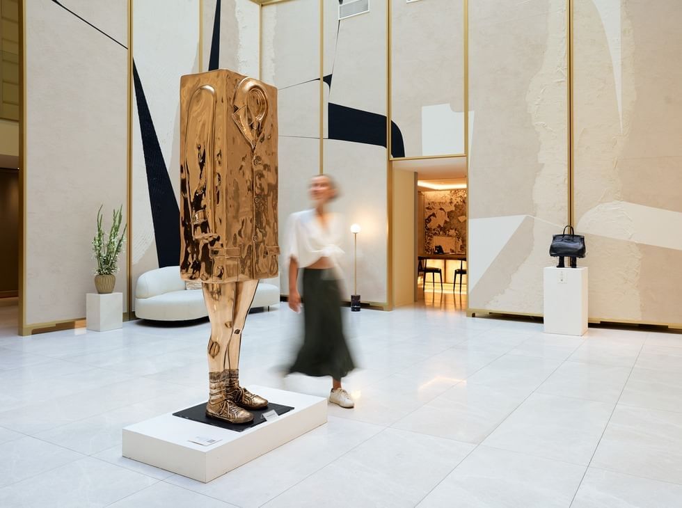 An abstract golden sculpture on a pedestal in a modern interior with plants and art at Almanac Palais Vienna