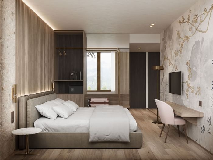 TV mounted above a work desk facing the bed, with a closet by the window in the Comfort Room at Hotel des Innovations