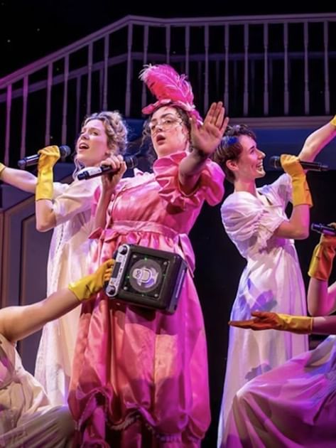 Performers in period costumes with yellow gloves act on stage in Pride and Prejudice* (*sort of)