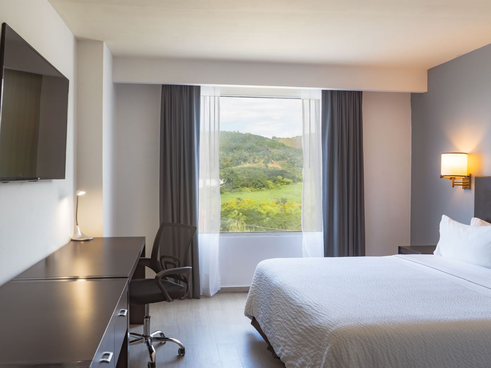 Work desk with bed, window and TV at Fiesta Inn 