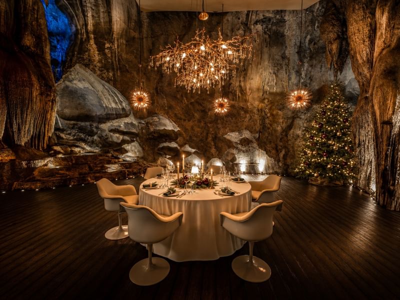 Jeff's Cellar's elegant dining table set in a dramatic cave setting with chandelier, starburst lights, and Christmas tree decorations celebrating New Year's Eve into 2027 New Year