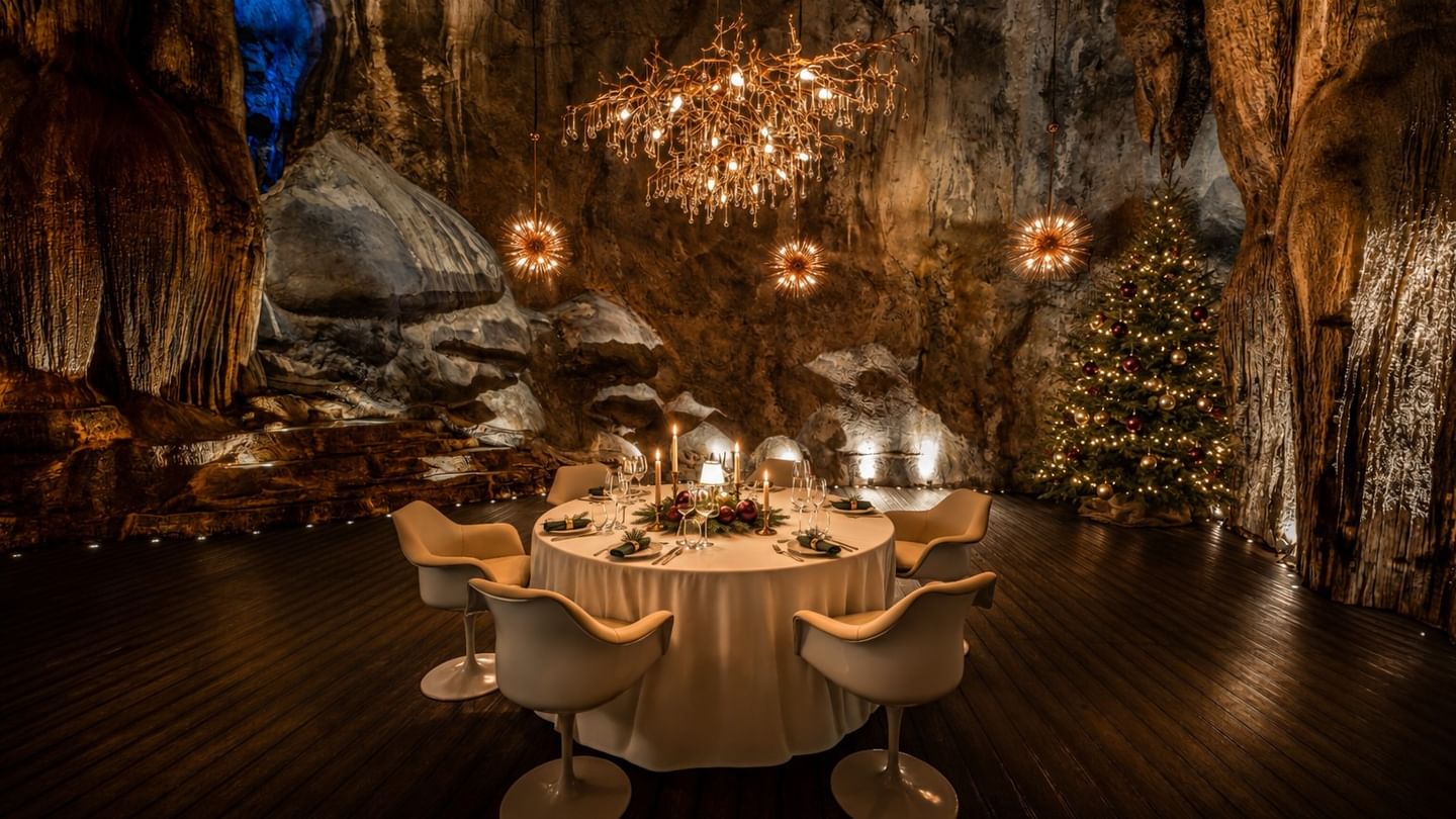 Jeff's Cellar's elegant dining table set in a dramatic cave setting with chandelier, starburst lights, and Christmas tree decorations celebrating New Year's Eve into 2027 New Year
