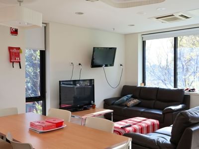 Modern living room with two couches, a dining table, and a TV at McFarlane's Hill Residences.