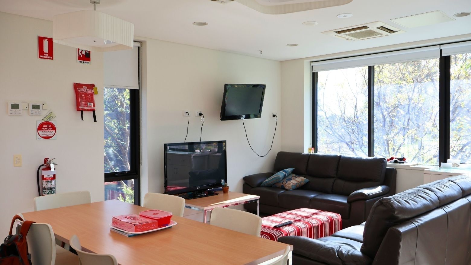Modern living room with two couches, a dining table, and a TV at McFarlane's Hill Residences.