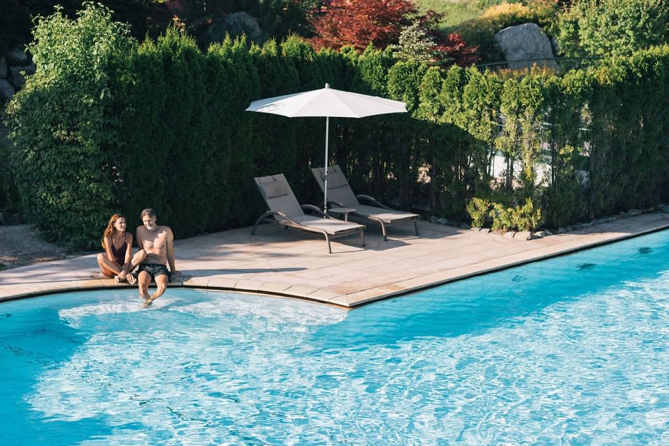 A couple seated on the edge of the pool at Liebes Rot Flueh
