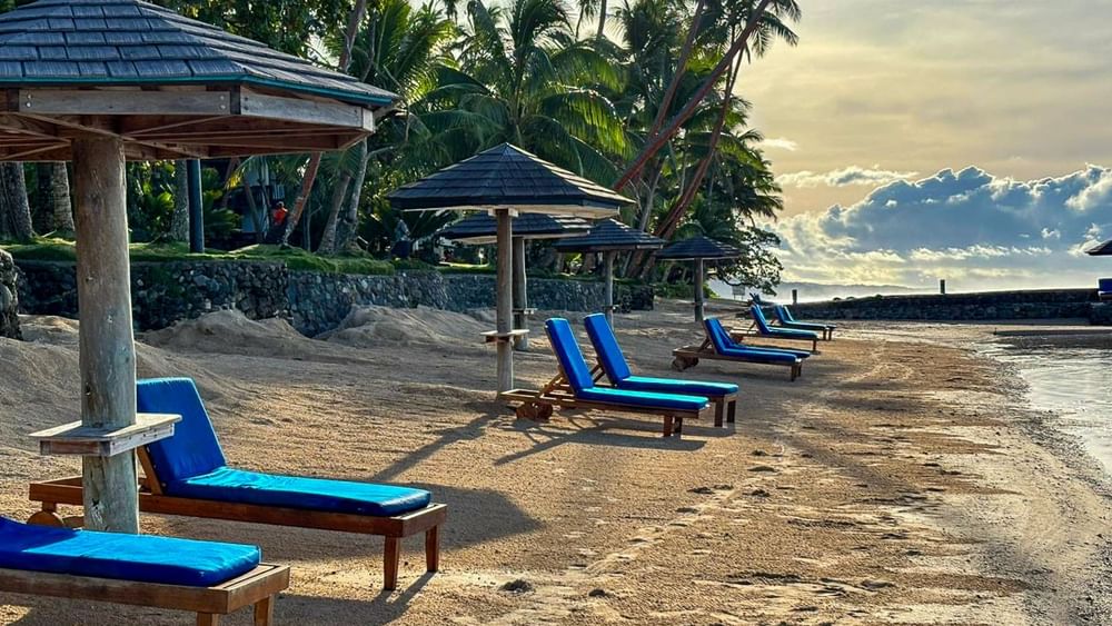 Sandy beach with lounge chairs under umbrellas at Warwick Fiji Resort and Spa in Korolevu.